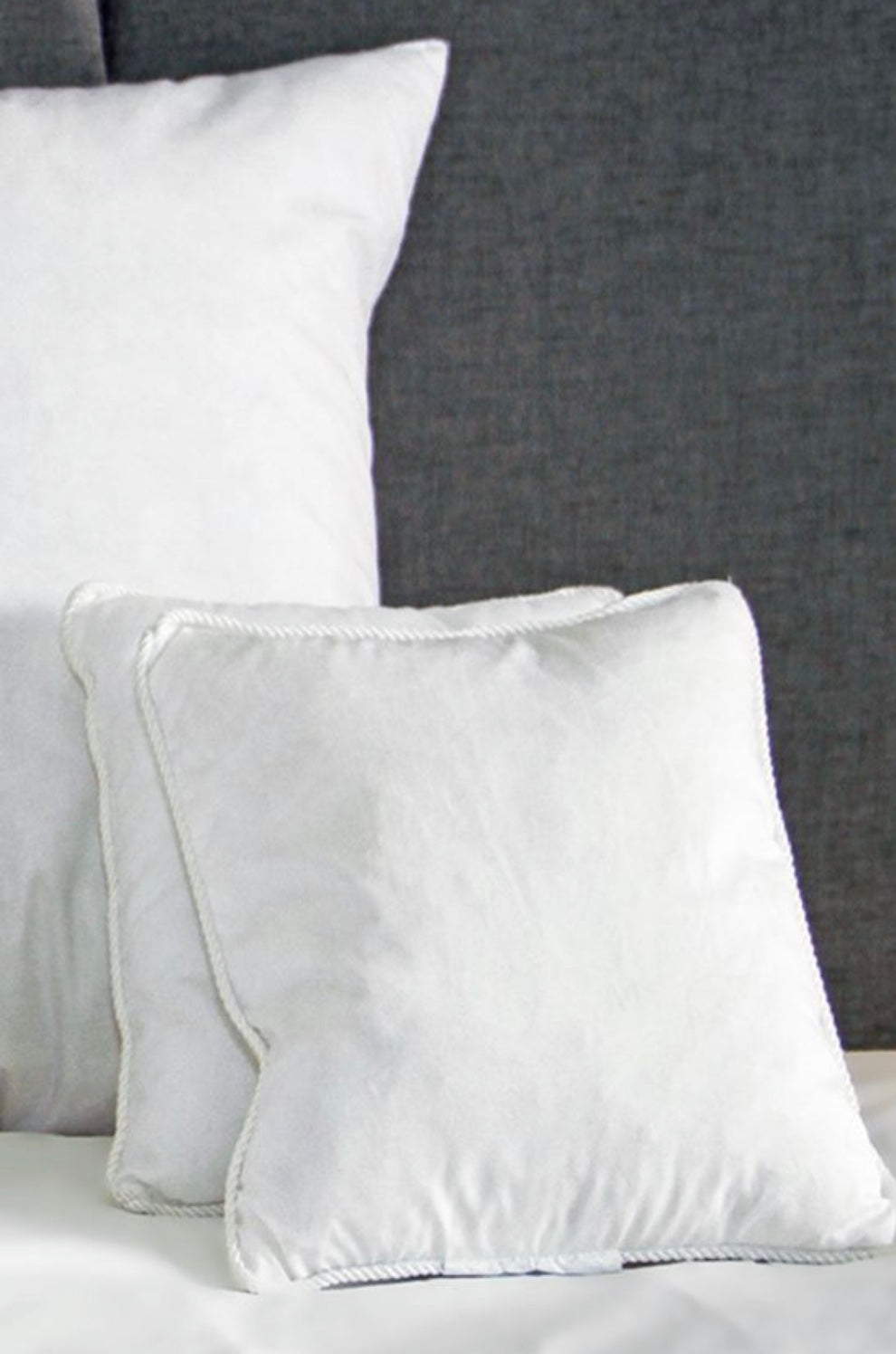 Deux petits coussins blancs sur un lit et un grand coussin