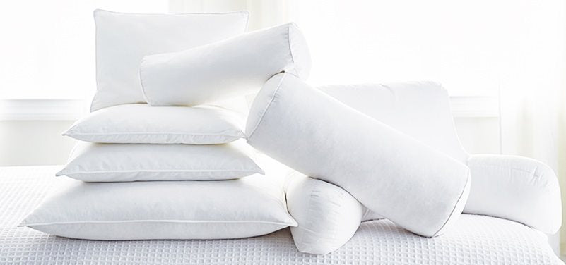 Plusieurs coussins blancs sur un lit avec différentes formes.