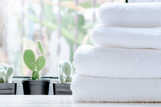 4 serviettes blanches empilées proprement sur un comptoir avec 3 pots de cactus