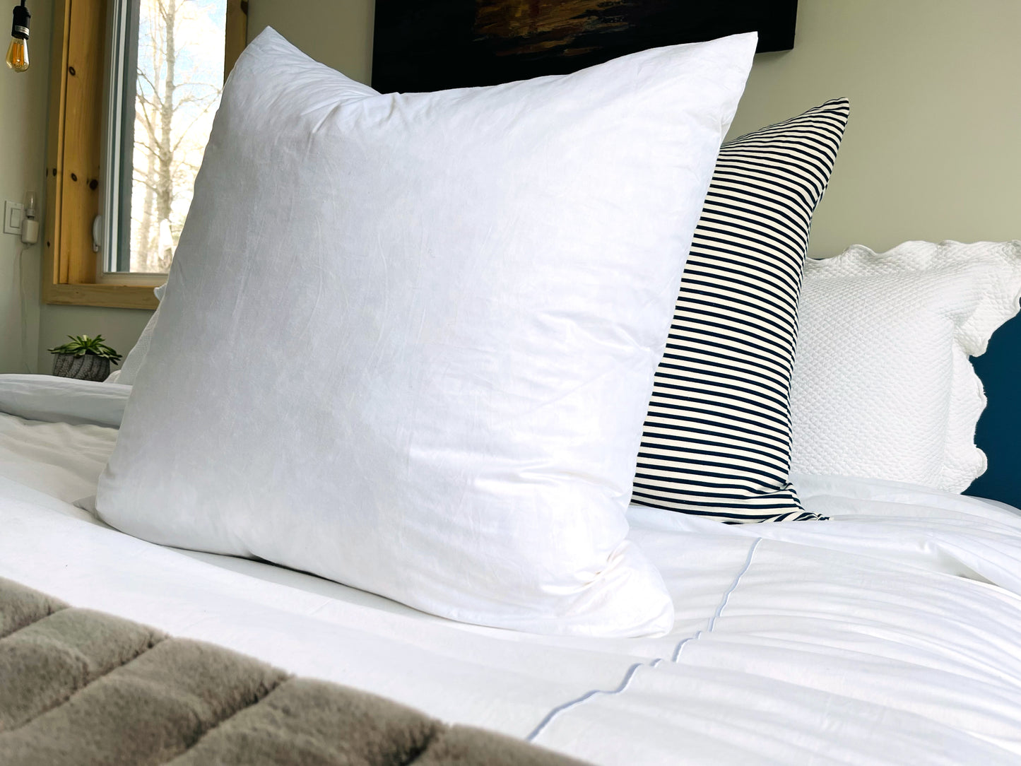 Coussin blanc et coussin rayé sur un lit 