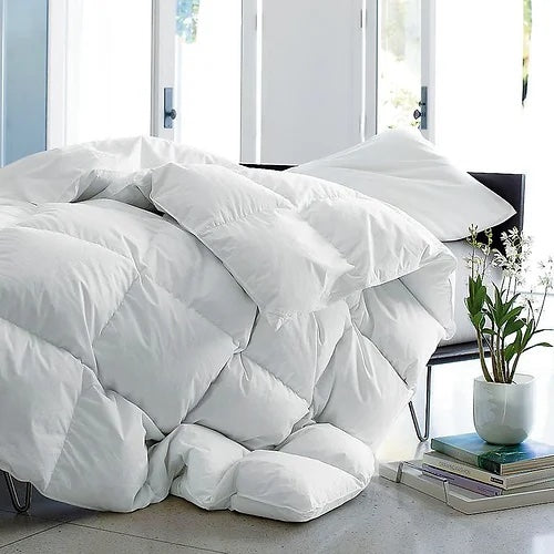 Couette de lit en duvet blanche avec pot de fleur blanc et livres empilés en dessous