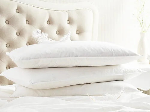 Pile d'oreiller blanche sur un lit blanc avec une tête de lit blanche