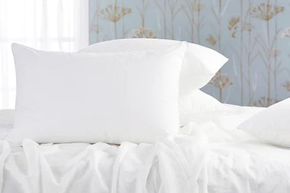 Oreillers blanches sur un lit blanc avec une fenêtre ensoleillée